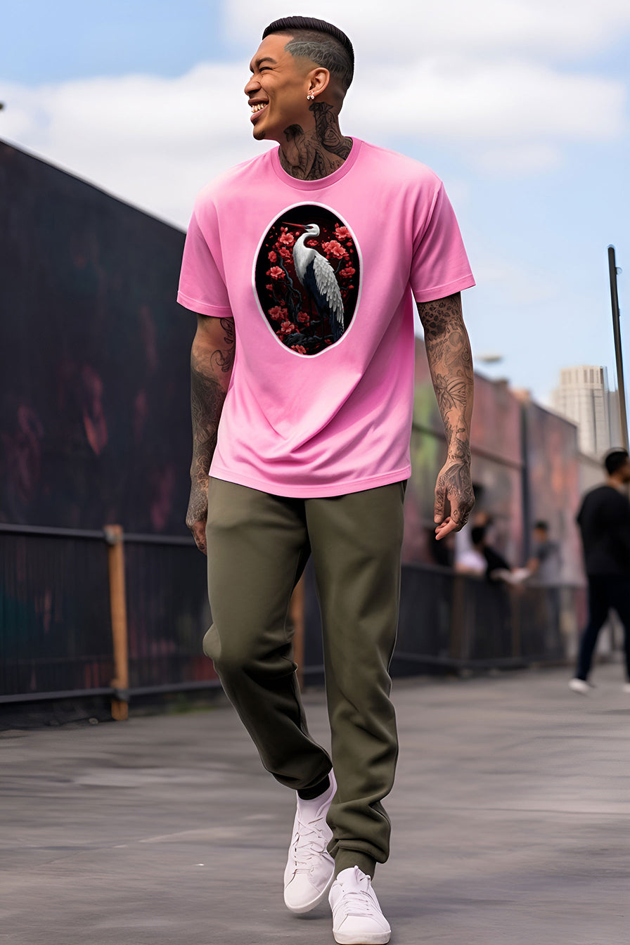 young tattooed man wearing an Azalea-pink graphic t-shirt featuring a Crane with cherry blossom trees print