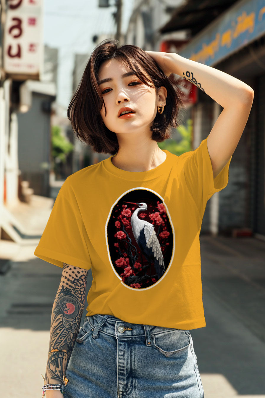 young tattooed woman wearing a yellow graphic t-shirt featuring a Crane with cherry blossom trees print